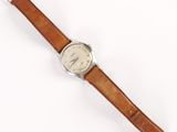 un gros plan d'une montre sur une surface blanche avec un fond blanc