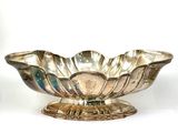 a silver bowl on a stand on a white surface