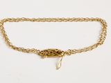 un gros plan sur un bracelet à chaîne en or orné d'une breloque en forme de feuille