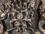 a close up of a metal vase with a face on it