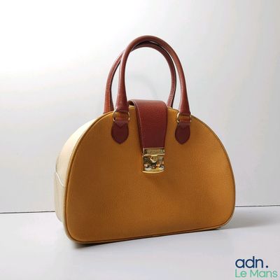 un sac à main beige et marron posé sur une surface blanche