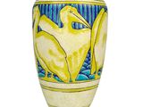 a yellow vase with a bird on it on a white surface