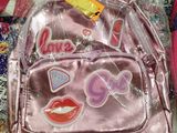 a pink backpack with stickers on it sitting on a table