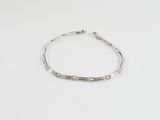 un bracelet en argent posé sur une table blanche, sur fond blanc