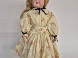 an image of a doll with blonde hair wearing a yellow dress and black shoes