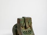une image représentant une petite sculpture en bronze représentant un visage, sur fond blanc
