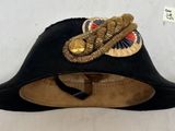 chapeau de pirate noir orné d'une bordure dorée et d'une plume sur le dessus
