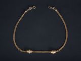 a gold chain bracelet with three beads on a black background
