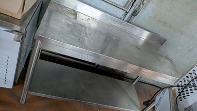 a stainless steel table with a metal shelf underneath it