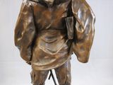 a bronze statue of a man with a book on a stand