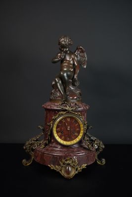 une horloge surmontée d'une statue, posée sur une table