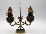 une image représentant une paire de bougeoirs noirs et dorés posés sur un socle