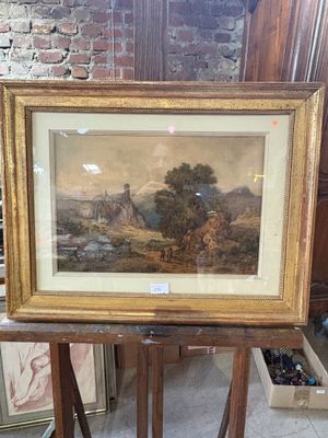 painting of a landscape in a gold frame on a wooden stand