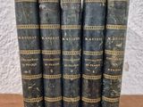 a set of five old books sitting on top of a wooden table