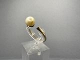 a gold ring with a pearl on it on a clear stand