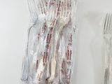 a lot of forks and spoons wrapped in plastic