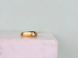 un gros plan d'une bague en or sertie d'un diamant, posée sur un bloc de marbre