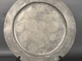 a silver plate on a black stand on a gray background