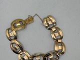 a close up of a gold chain bracelet on a white surface