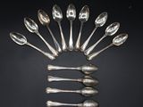 six cuillères en argent disposées en cercle sur une surface noire