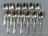 six cuillères en argent sont disposées en rangée sur une table