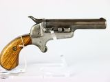 un vieux pistolet avec une crosse en bois, posé sur un socle transparent