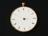a gold clock with roman numerals on a black surface