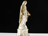 a statue of the virgin of guadalupe on a white table