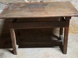 une petite table avec un plateau en bois posée sur un sol en ciment