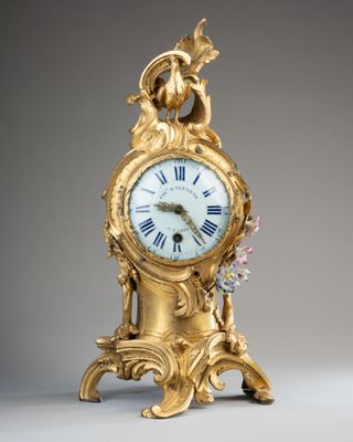 une horloge en or surmontée d'un oiseau
