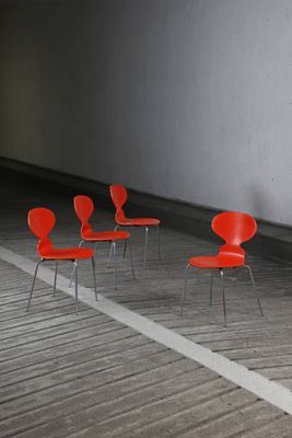 four red chairs are lined up in a row in an empty room