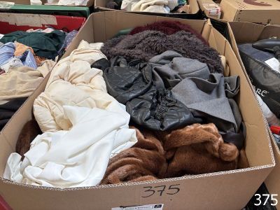 une boîte en carton remplie de nombreux vêtements et d'un ours en peluche