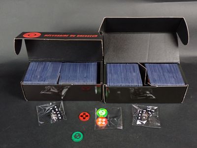 une boîte de cartes et une boîte de dés posées sur une table
