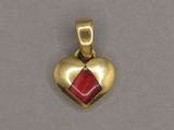 a gold heart shaped pendant with a red stone in the center