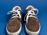 brown woven leather sneakers with white laces on a blue background