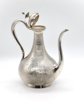 an antique silver tea pot with a bird on top of it