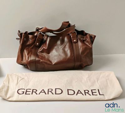 Le grand sac marron est posé à côté d'un sac blanc.