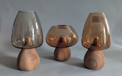 three glass vases with wooden bases on a table