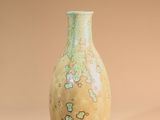 a green vase sitting on a beige surface