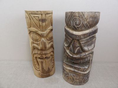 deux statues de tiki en bois posées l'une à côté de l'autre sur une table