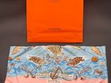 an orange shopping bag sitting on top of a table next to a pink bag