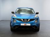 the front of a blue nissan juke suv parked in a showroom