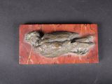 an image of a bronze sculpture of a bird on a red marble block