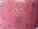 a pink vase with flowers on it sitting on a table