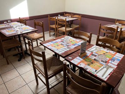de nombreuses tables et chaises dans un restaurant, sur lesquelles sont posés des journaux