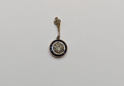un gros plan d'un pendentif argenté et bleu sur une surface blanche