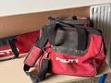 a red duffel bag sitting on a table next to a radiator