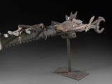 une sculpture représentant un dragon, réalisée en métal et posée sur un socle métallique
