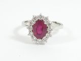 a close up of a ring with a ruby stone surrounded by diamonds