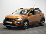 Une voiture orange est garée dans une pièce au sol à carreaux.